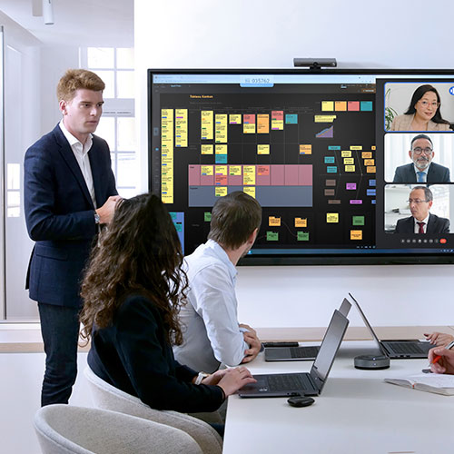 Team diskuterer projektstrategi foran smartboard til undervisning og møder i mødelokale.