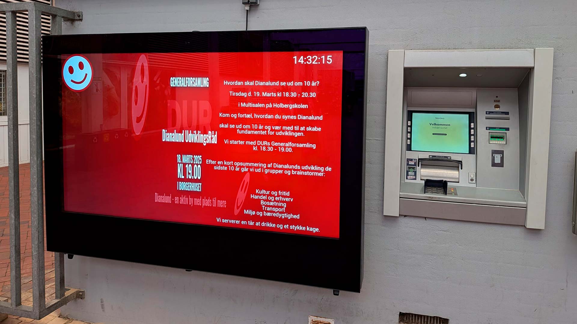 Udendørs digital informationsskærm i Dianalund, der viser arrangementer ved en pengeautomat.