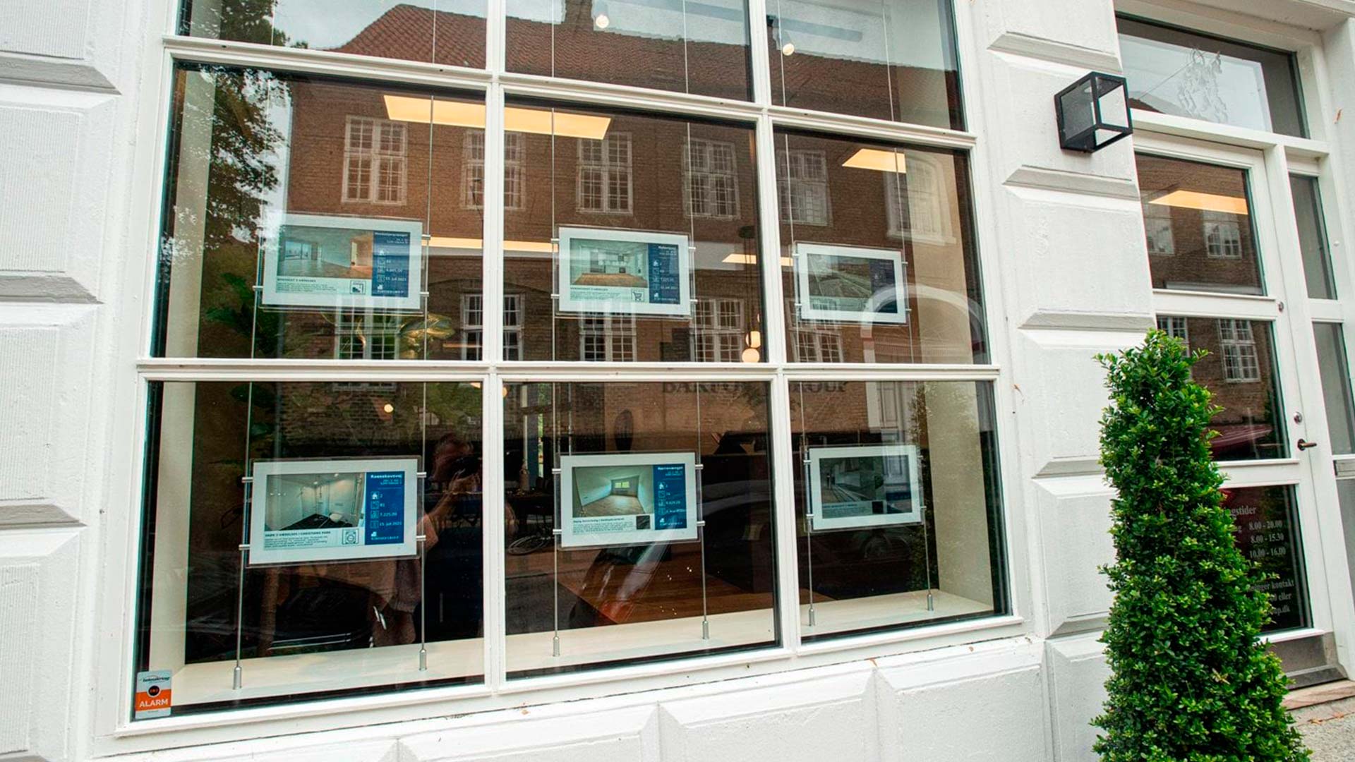 Digitale mæglerskilte til ejendomsmæglere i et vindue hos Barfoed Group.
