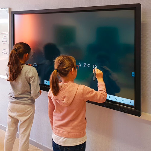 Elever arbejder aktivt med opgaver på smartboard til undervisning i klasseværelse.