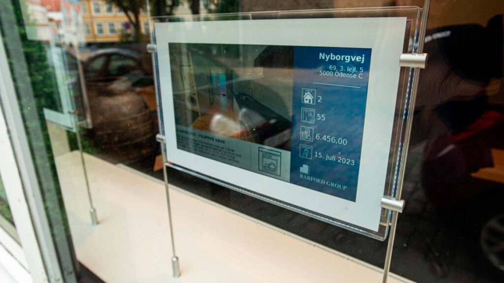 Et digitalt mæglerskilt i vinduet hos ejendomsmægler Barfoed Group.
