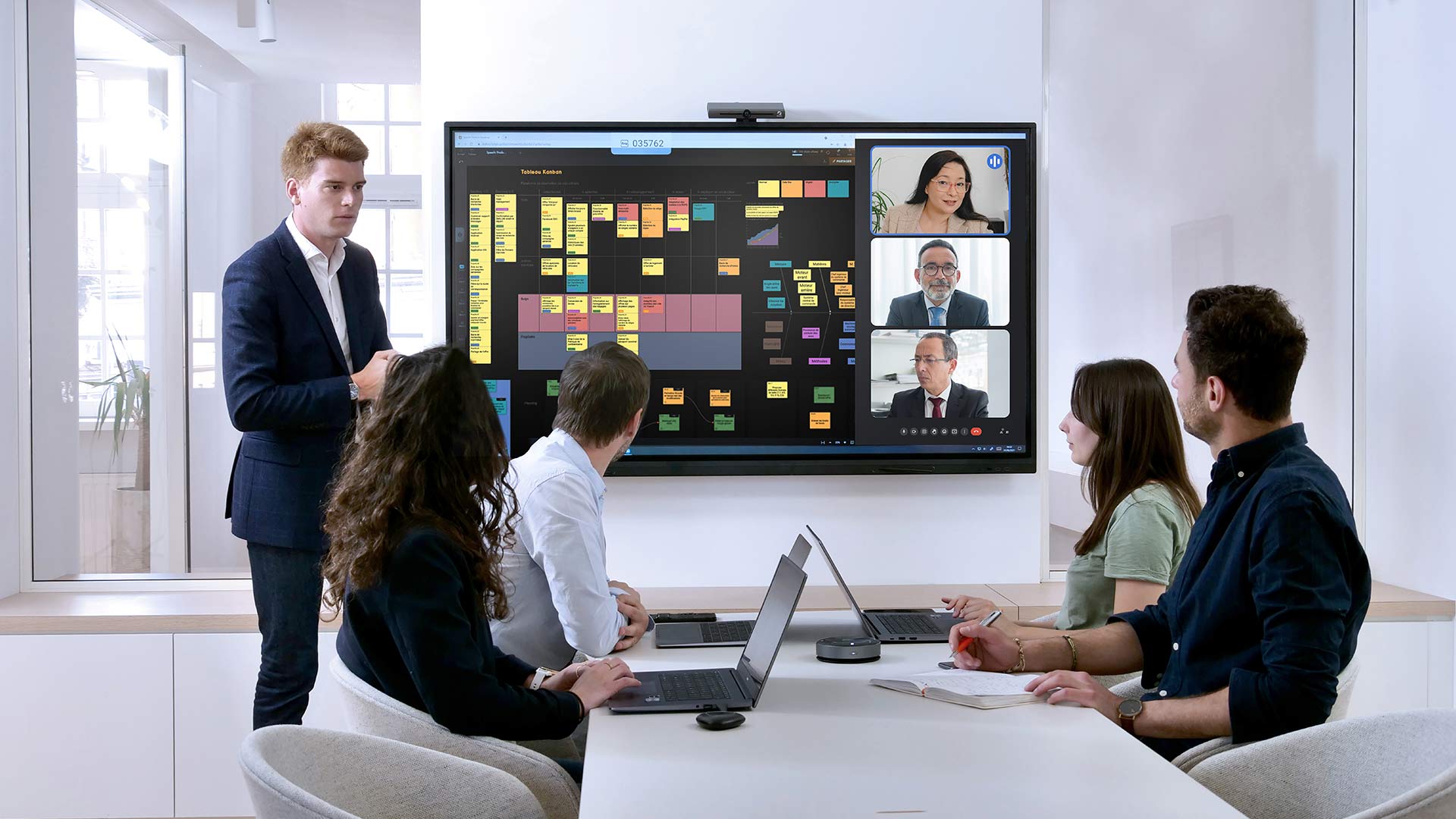 Møde med kolleger, der gennemgår indhold på et Speechi smartboard og videosamtale.