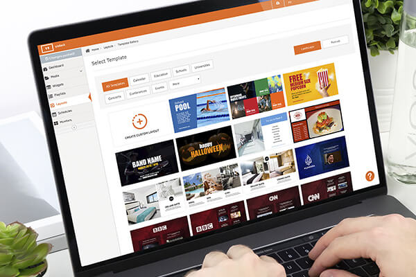 PC med infoskærm-software fra Visualsign, der viser et udvalg af skabeloner og layouts til digital signage og visuel kommunikation.