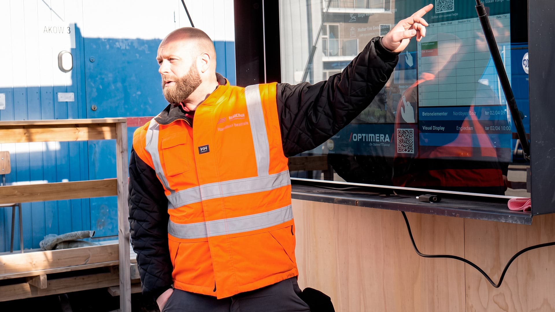 Byggeleder Johnny Engel fra Sjælsø Management, informerer håndværkere ved morgenmøde ved infoskærm med touch til byggeplads