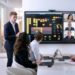 Team diskuterer projektstrategi foran smartboard til undervisning og møder i mødelokale.