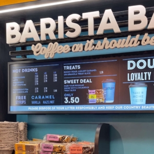 Stretched display monterat ovanför disken på kaféet, som visar priser och erbjudanden