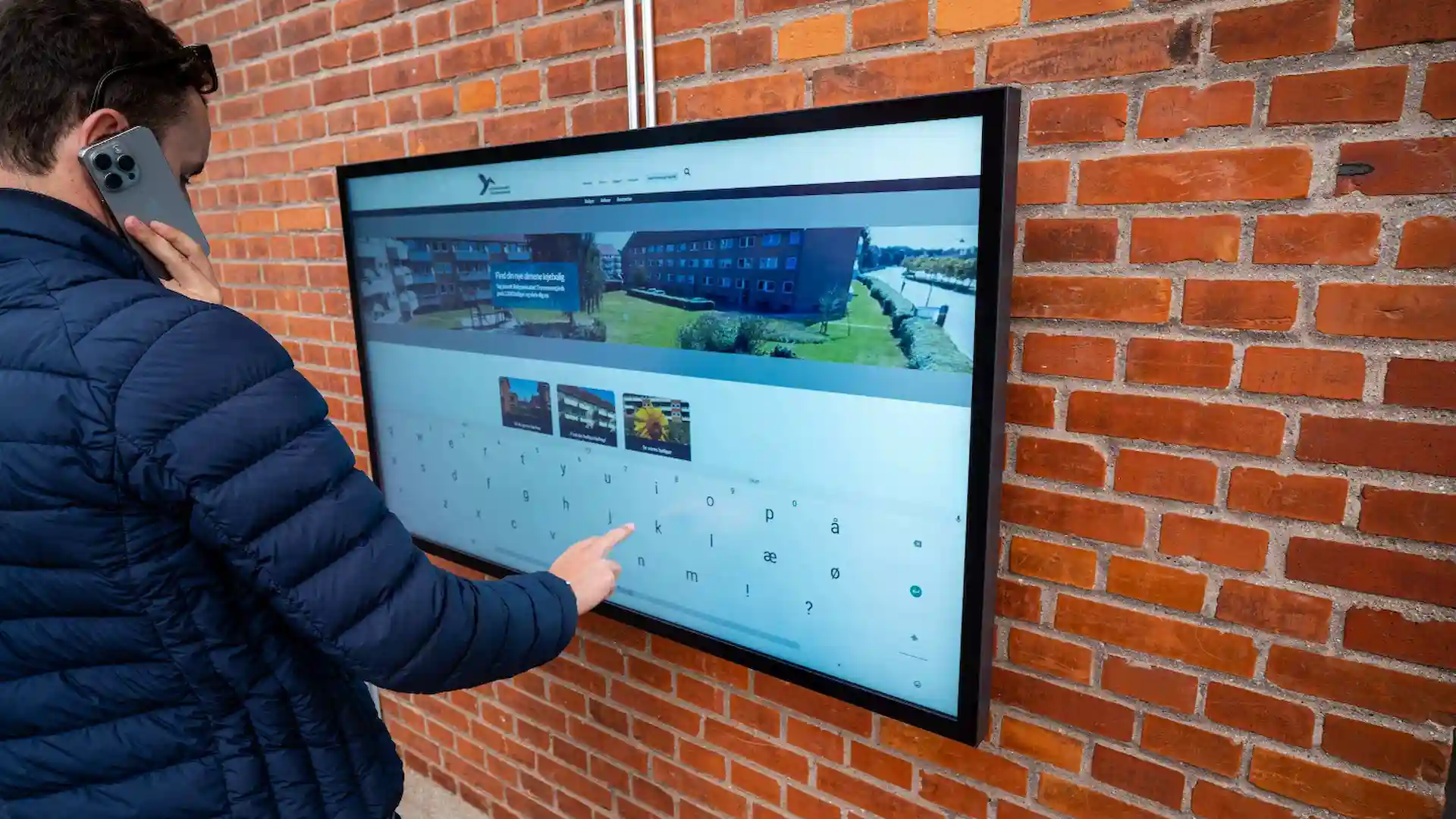 Udendørs touch-infoskærm på husvæg hos Boligselskabet Tranemosegård